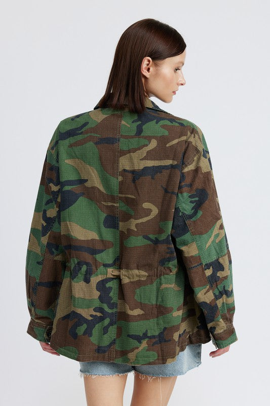 Oversized camo jacket with a collared neckline, long sleeves, and practical pockets. Made of 100% cotton with zipper and button closures.