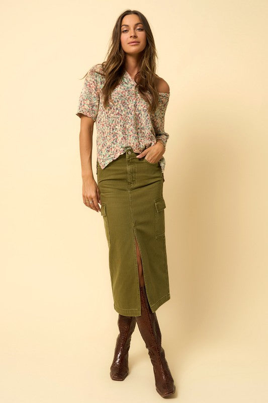 Olive green denim cargo midi skirt with a front slit and seven functional pockets. Features a button closure and regular fit.