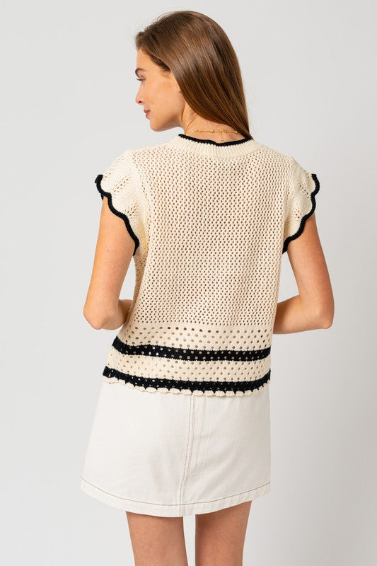 A chic white sweater top with cap ruffle sleeves and bold black color-contrast trim, featuring a round neckline, and playful detailing.