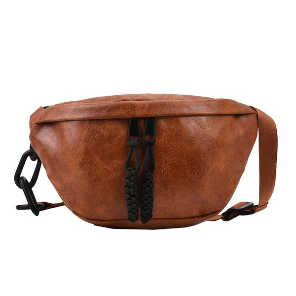 Cognac sling bag with a soft vegan leather exterior, chunky black chain accent, and adjustable strap. Includes zip pockets and a solid design.