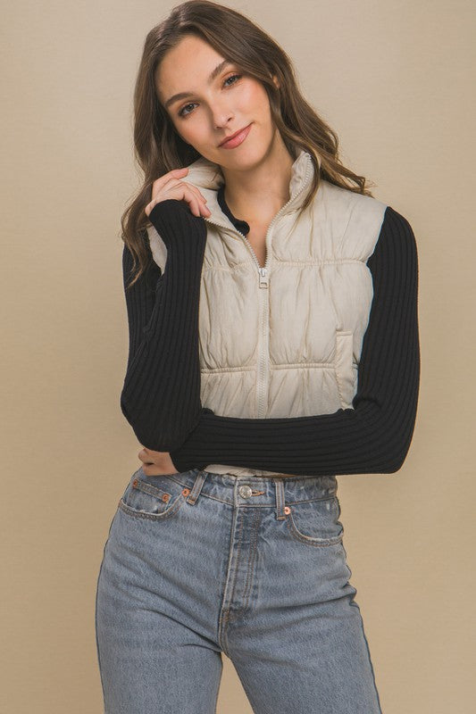 Cream sleeveless puffer vest with a high collar, cropped length, and side pockets.