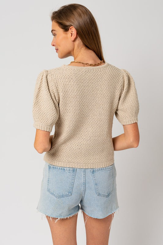 Woman's textured oatmeal sweater with a round neckline and short puff sleeves.