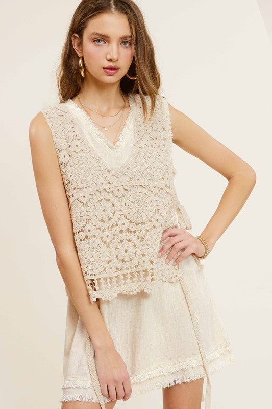 Sleeveless crochet vest with scoop neckline and side self-tie details.