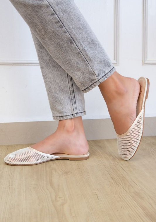 Woman wearing champagne Levi slip-on mesh flats with round toe and open back for chic summer style.