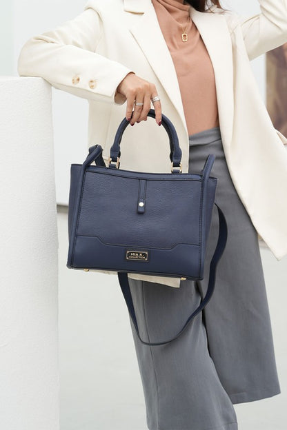 Woman holding navy Melody Vegan Leather Tote by top handle, showing structured design.