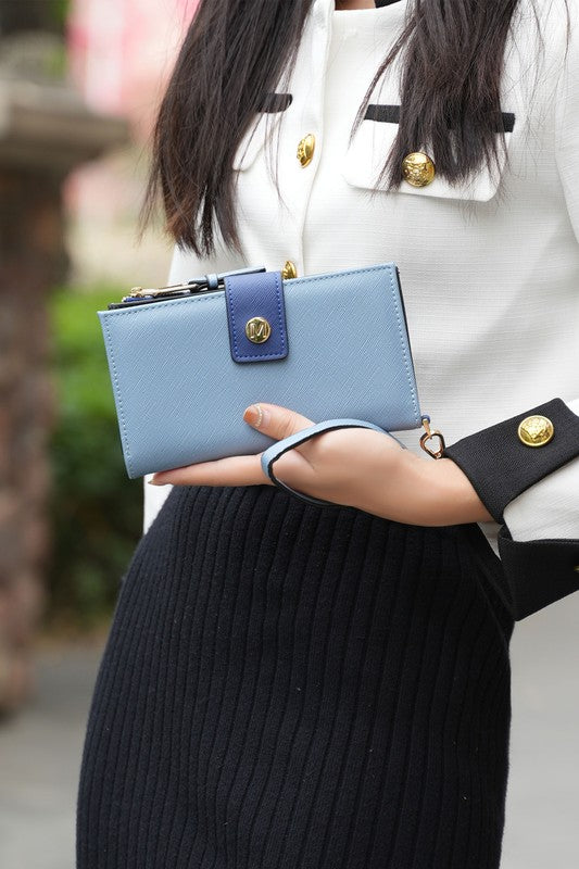 Woman holding MKF Collection Solene vegan leather wristlet wallet in denim blue with gold-tone hardware.