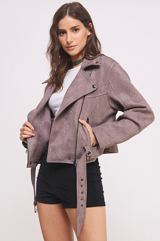 Grey belted long sleeve zippered suede moto jacket with front zippers, snap details, and two zipper pockets.