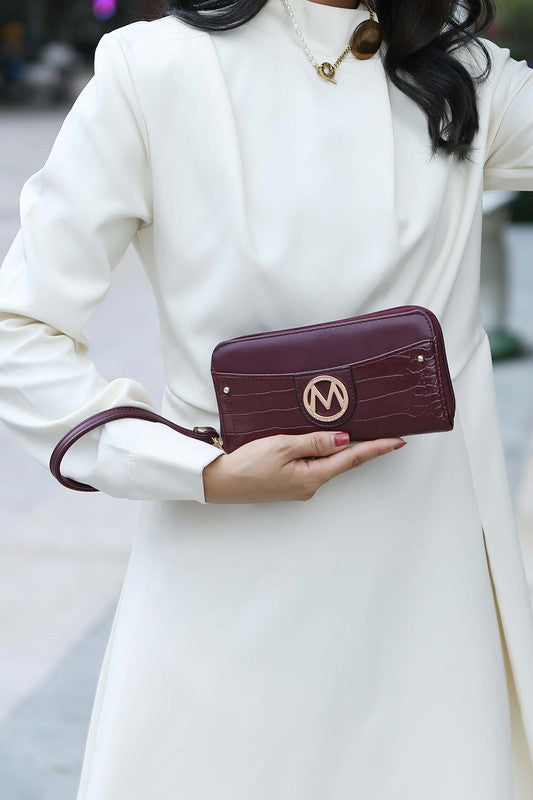 Model holding Eggplant Nora wallet with gold MK logo detail.