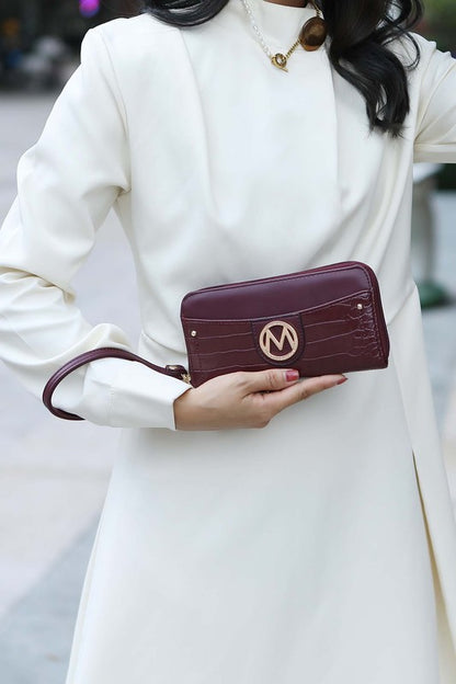 Model holding Eggplant Nora wallet with gold MK logo detail.