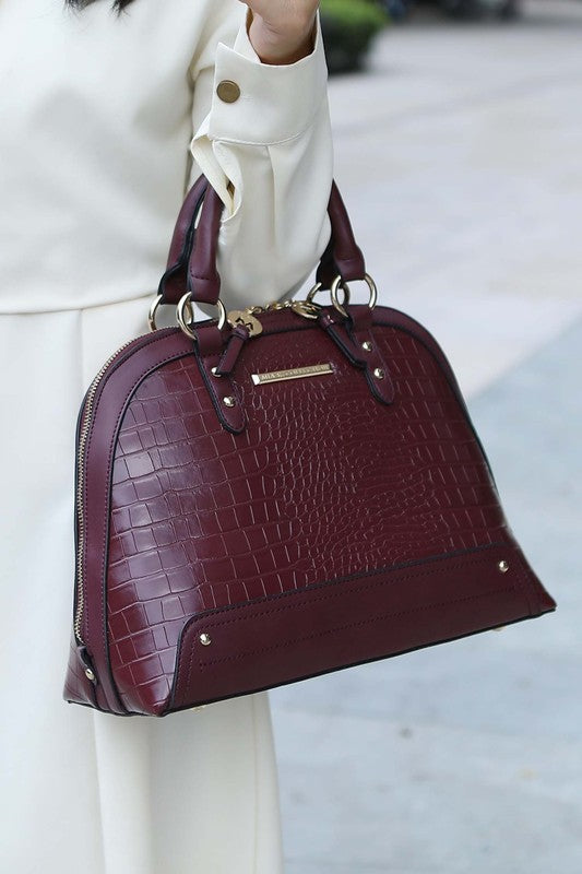 Model holding Eggplant Nora Satchel showing croco pattern and gold hardware.