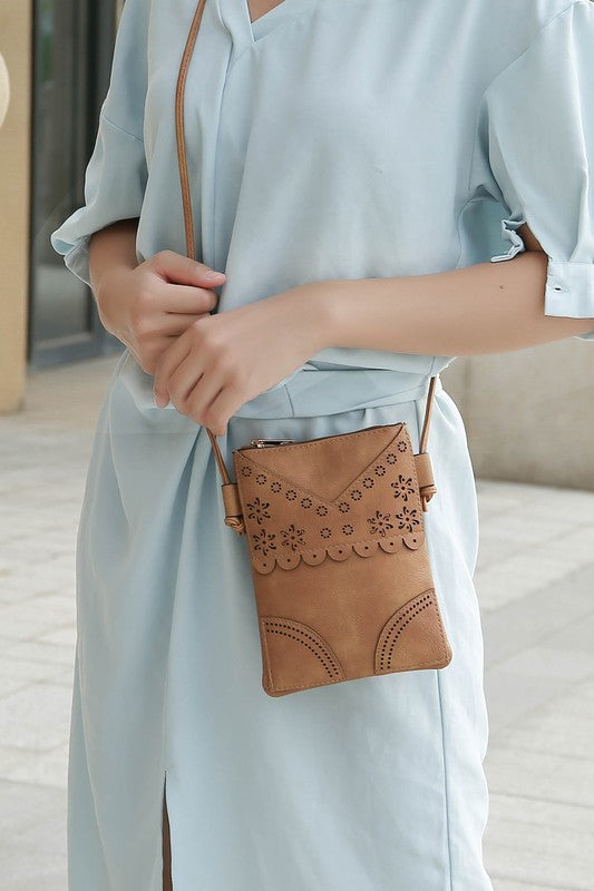 Model wearing beige Amentia Crossbody Bag over shoulder showing laser-cut floral design.