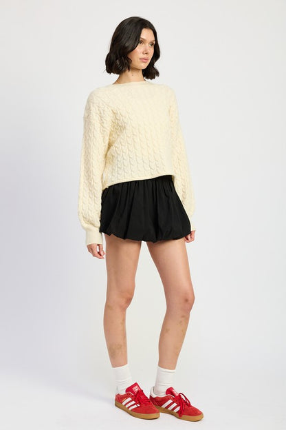 Side view of Kuuma Cable Knit Cropped Sweater showing dropped shoulders and balloon sleeves.