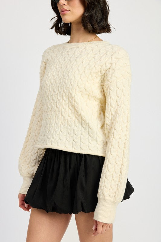 Close-up of ivory Kuuma Cropped Sweater showing chunky cable knit texture and soft fabric.