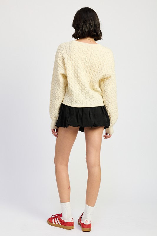 Back view of Kuuma Cable Knit Cropped Sweater in ivory with ribbed hem and relaxed fit.