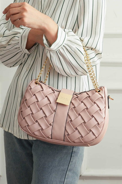 Woman holding pink Solari Braided Chain Shoulder Bag in crook of elbow, showcasing woven design and gold-tone chain strap.