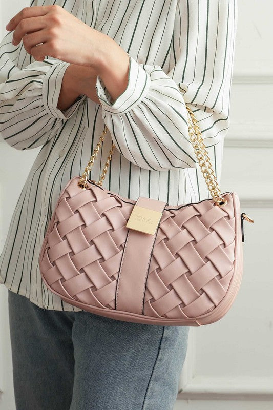 Woman holding pink Solari Braided Chain Shoulder Bag in crook of elbow, showcasing woven design and gold-tone chain strap.