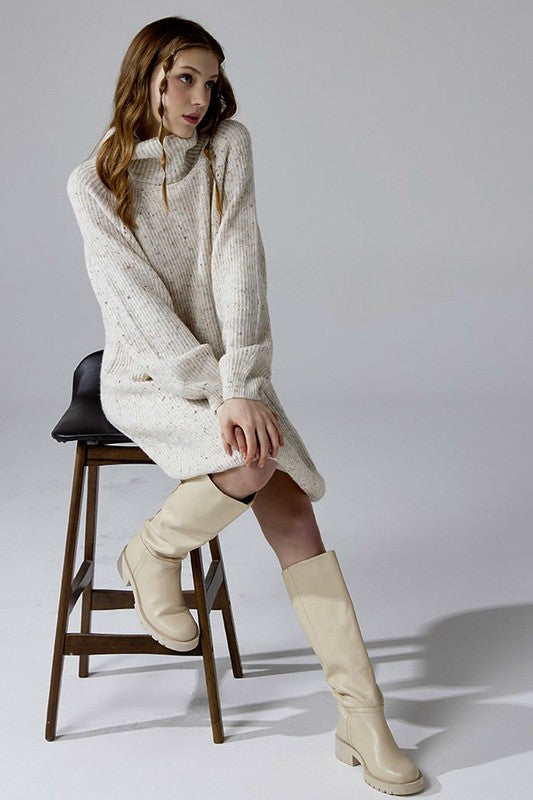 Model wearing ivory sweater dress turtleneck style with playful confetti knit.