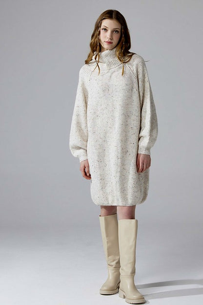 Model plus size ivory turtleneck sweater dress with balloon sleeves.