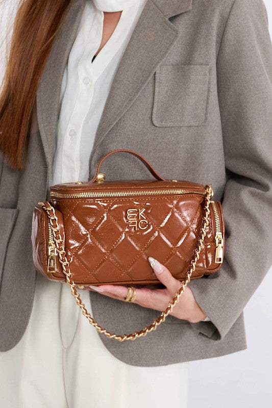Woman holding brown MKF Fortuna quilted crossbody purse with gold-tone accents and top handle.