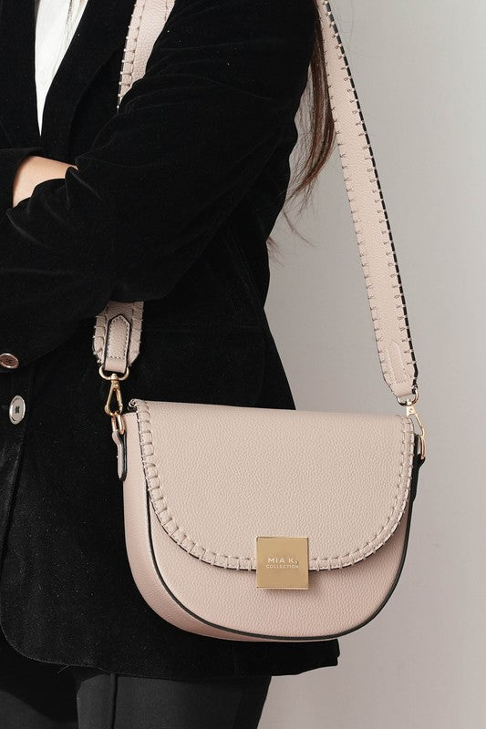 Woman wearing taupe Isa crossbody bag over shoulder with adjustable strap.