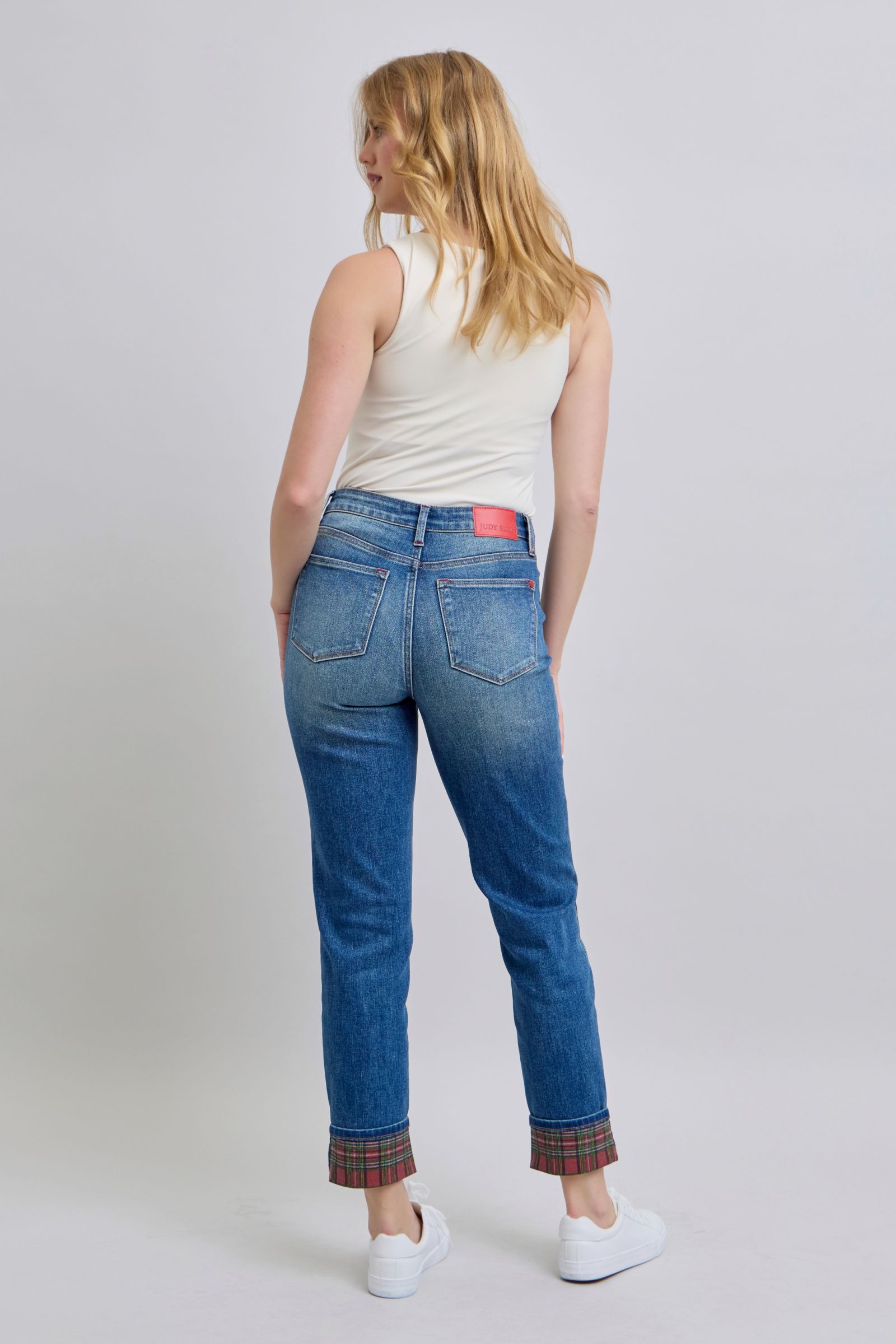 Women's mid rise, medium-wash straight-leg jeans with red and green plaid cuffs.