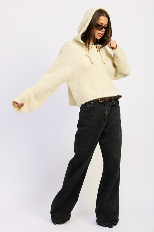 Model in ivory Juniper fringe hoodie with drawstrings, styled with black wide-leg jeans 