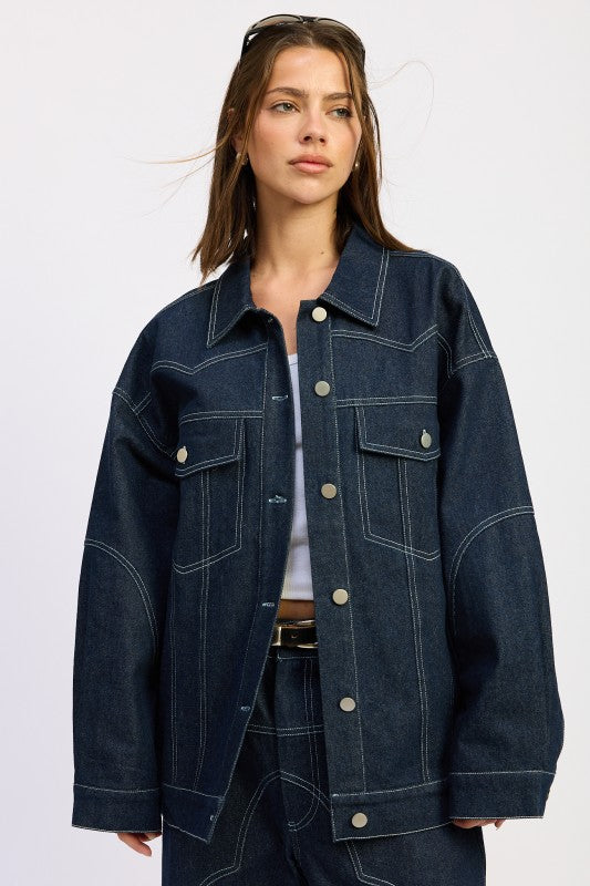 Front view of model wearing Brin Oversized Denim Jacket in dark wash with contrast stitching.