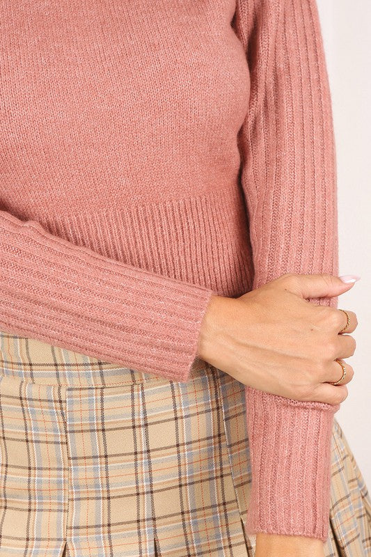 Cropped mock neck sweater in pink with a melange pattern, long raglan sleeves, and stretchy fabric.