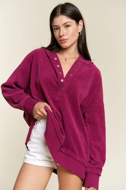 Model wearing Kenzie Plus Size Hooded Sweatshirt in magenta with V-neck button placket.