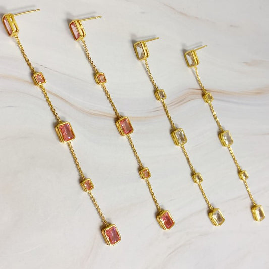Flat lay of blush pink and clear variants of Five Stones Dangle Drop Earrings side by side