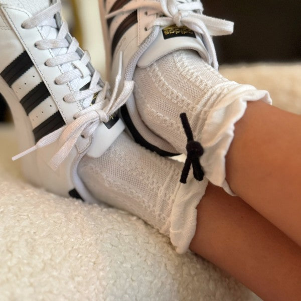 Woman wearing white Yarn Bow Socks with sneakers showing whimsical bow detail.
