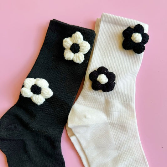 Flat lay of black and white Puffy Daisy Socks with 3D floral embellishments.