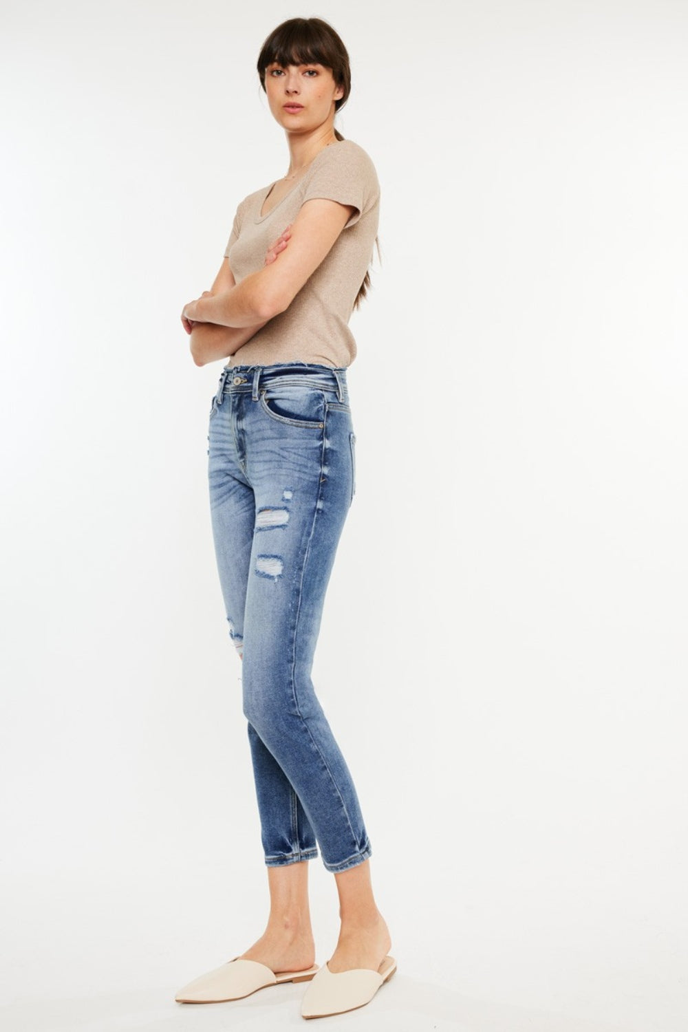 Medium wash high-rise mom jeans with distressed details and slightly stretchy fabric, offering a vintage-inspired, comfortable fit.