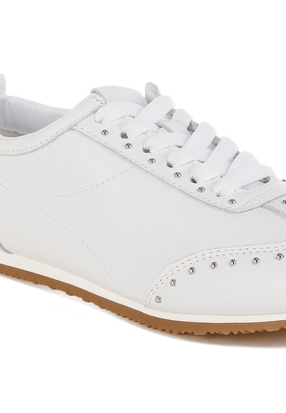 Close-up of white Odaya Studded Leather Sneakers by Rag Company, highlighting soft leather texture, stud embellishments, and contrast sole detail.