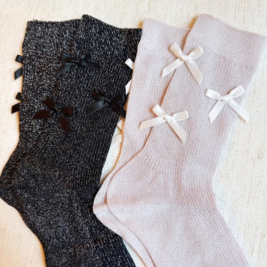 Flat lay of black and pink Shimmer Chic Bow Socks showing shimmer knit and satin bow details.
