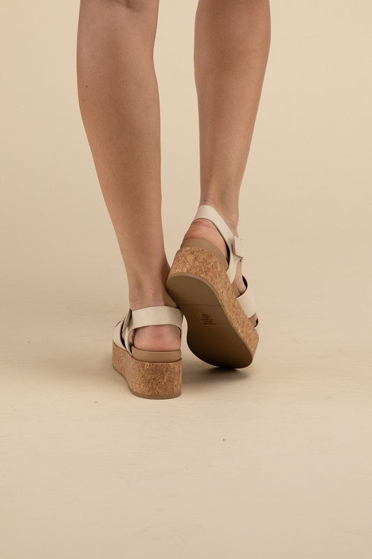 Beige platform wedge sandals with a buckle closure and 1.5" heel.