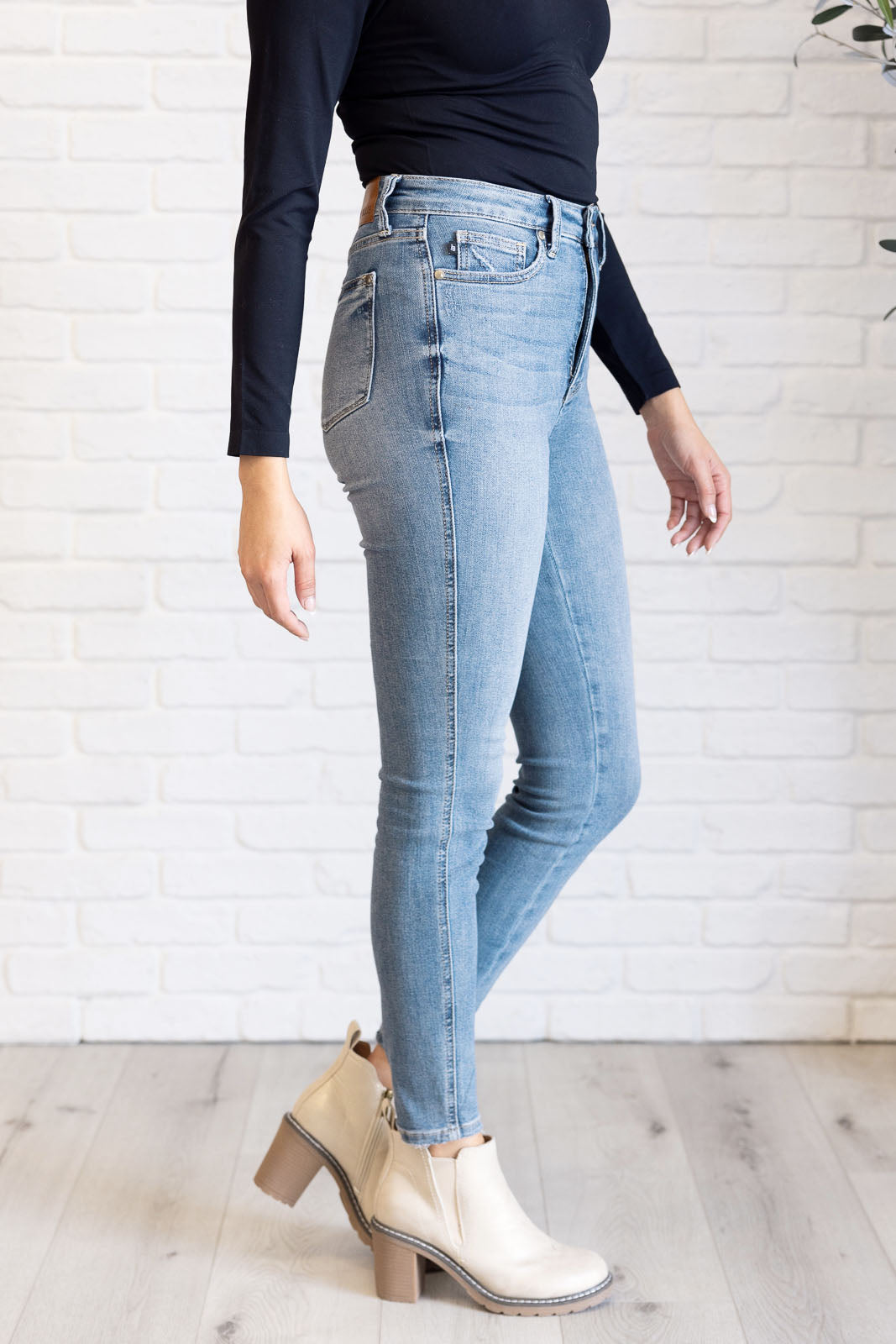 A side view of High Rise Skinny Jeans by Judy Blue in a light contrast wash, featuring a zip fly, tummy control panel, and high-rise waist for a flattering fit.