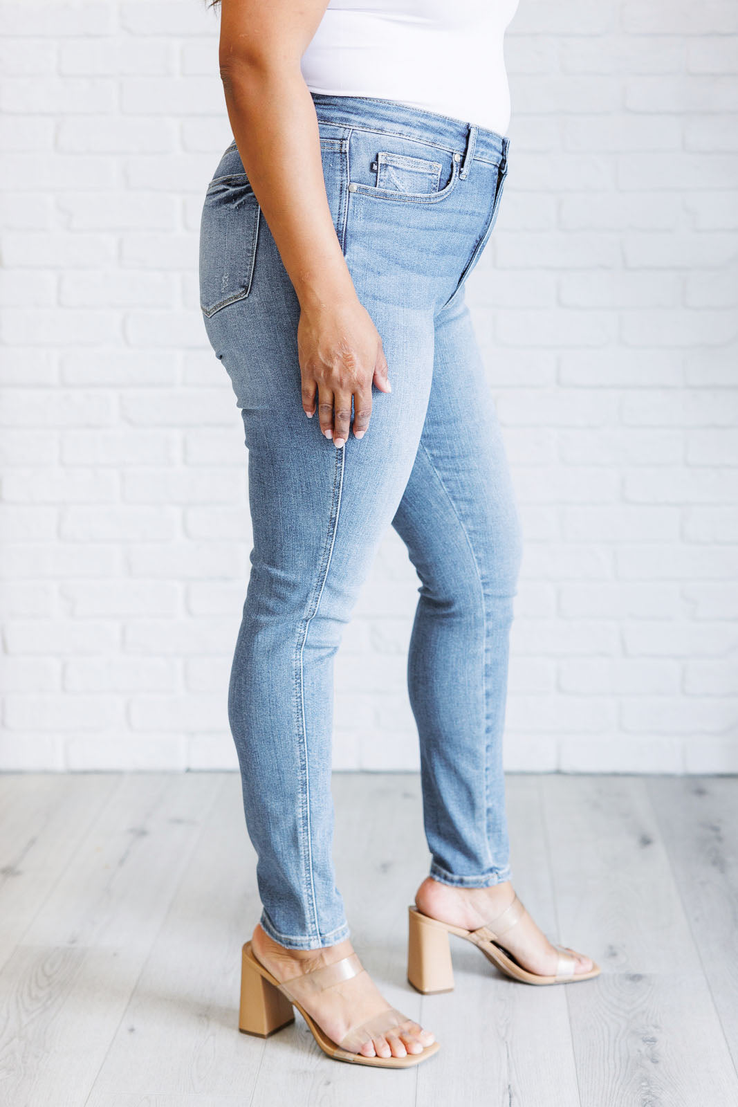 Side view of women in plus size High Rise Skinny Jeans by Judy Blue in a light contrast wash, featuring a zip fly, tummy control panel, and high-rise waist for a flattering fit.