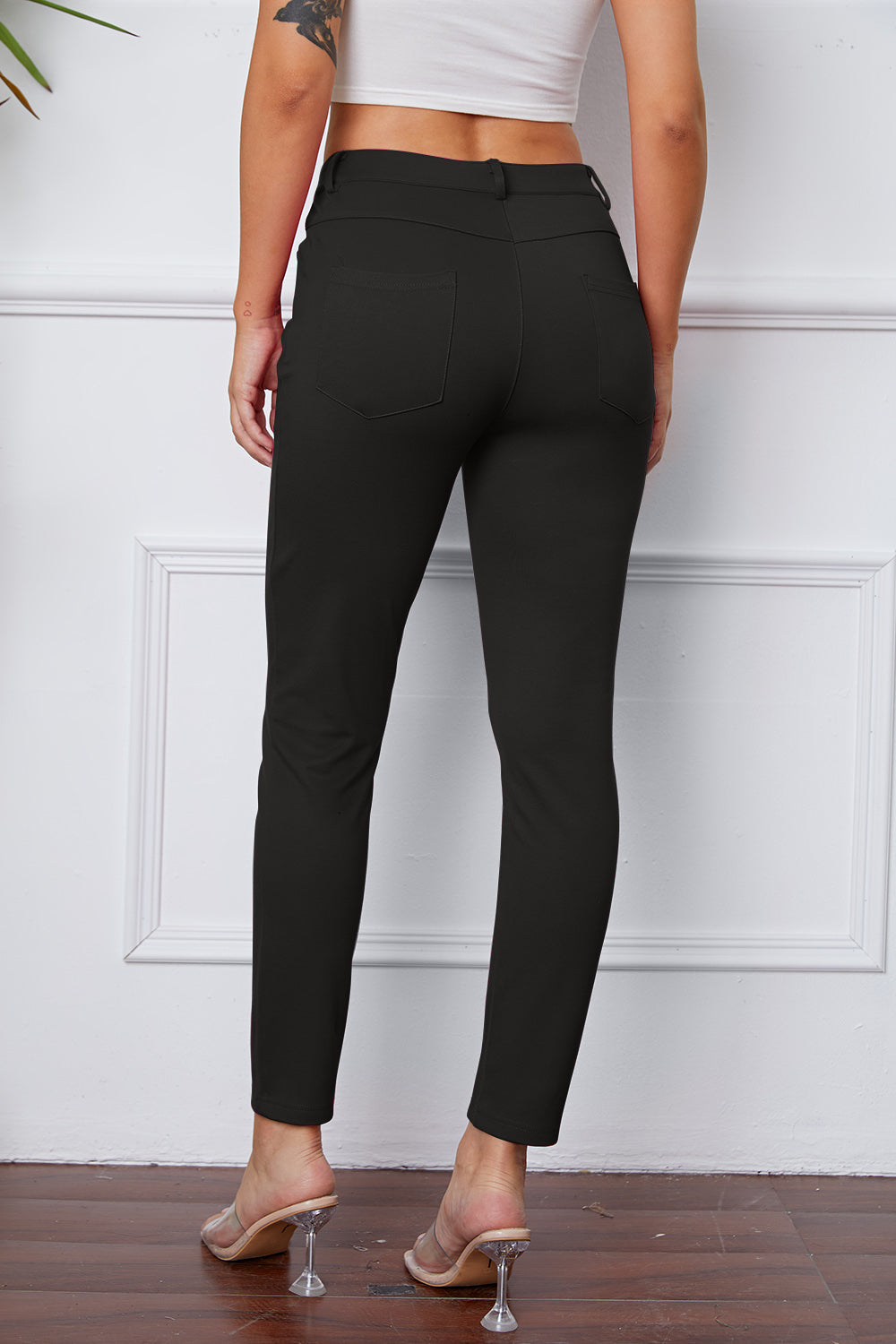 Black stretchy high-waisted pants feature pockets, a zip fly, and belt loops. 