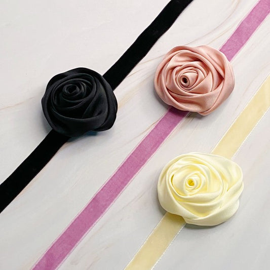 Trio of satin rose velvet sash necklaces arranged in cream, pink, and black
