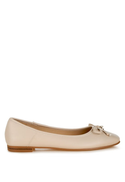 Side view of beige vegan leather flats featuring bow embellishment, cushioned insole, and flat heel for versatile wear.