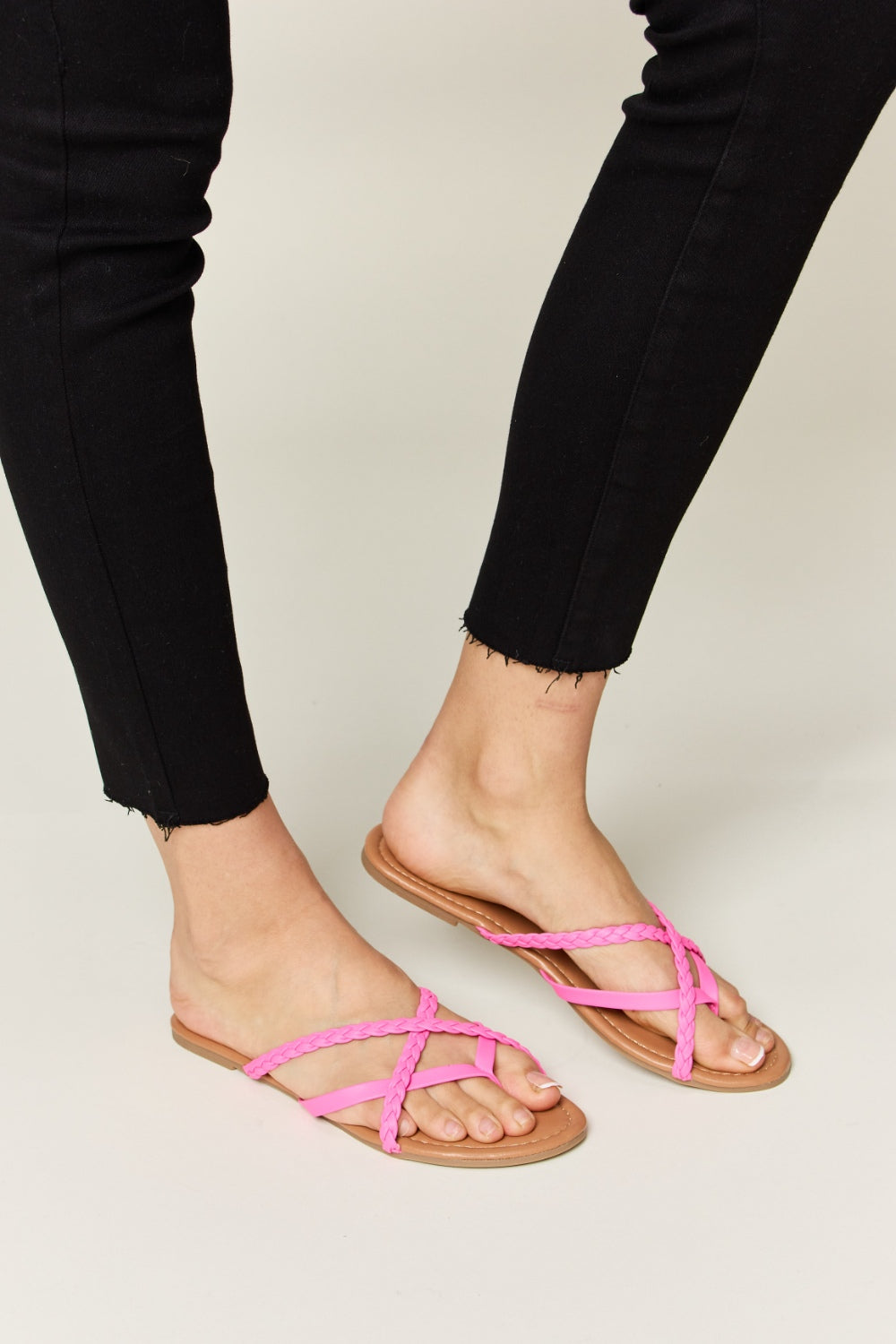 Hot pink crisscross open-toe sandals made from PU leather with a flat heel.