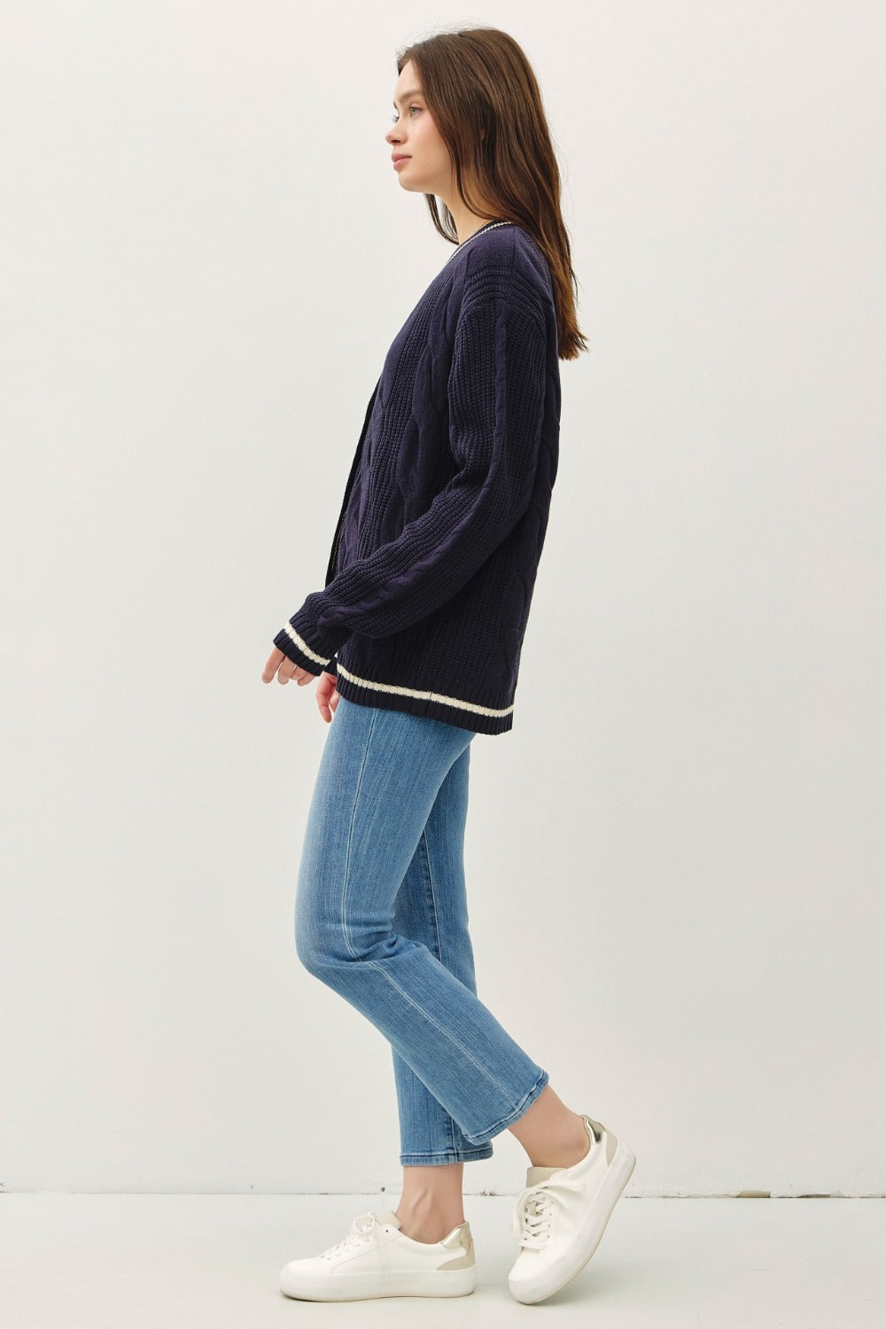 Navy and white contrast trim cable-knit cardigan with woven details and button closure.