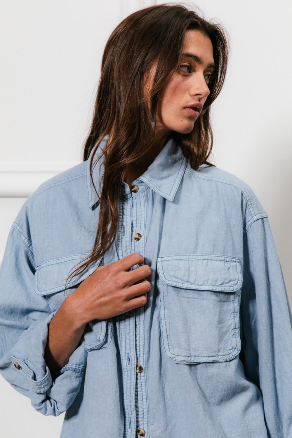 A denim button-down shirt with long sleeves, chest pockets, and detailed stitching. The shirt has a collared neckline and button closure.