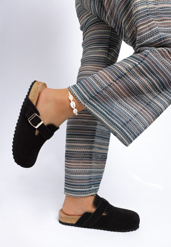 Model wearing Black Ratiha Mules showing side views, medial and lateral, in faux suede finish.