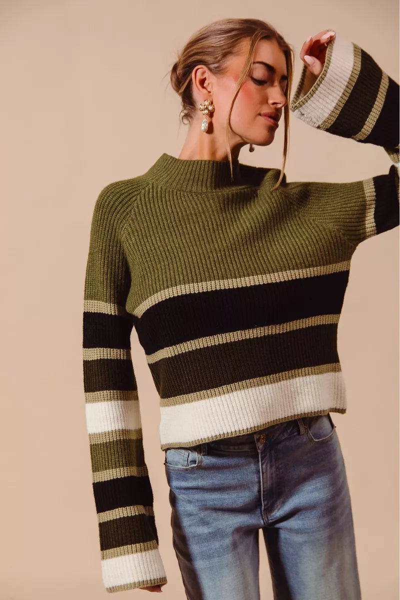 Lifestyle shot wearing Auden olive multi striped sweater with jeans.