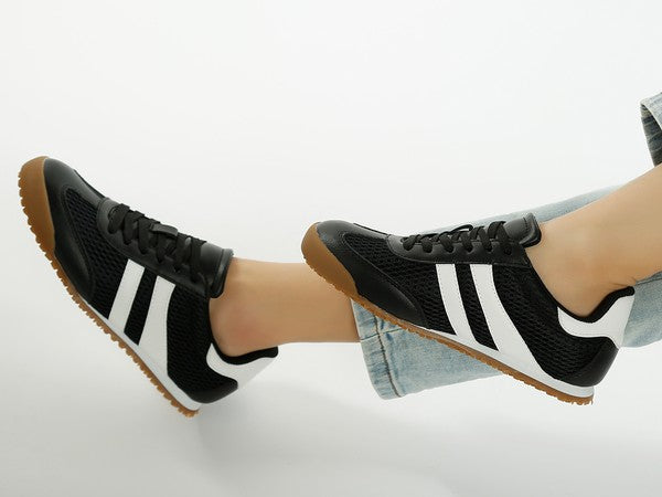 Side view of black Blaster sneakers with white stripes, featuring mesh material, lace-up closure, and lug sole – worn by model for sporty everyday style