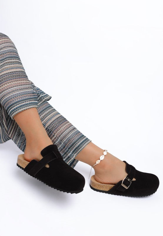 Model wearing Black Ratiha Mules showing medial and lateral sides with gold buckle strap detail.
