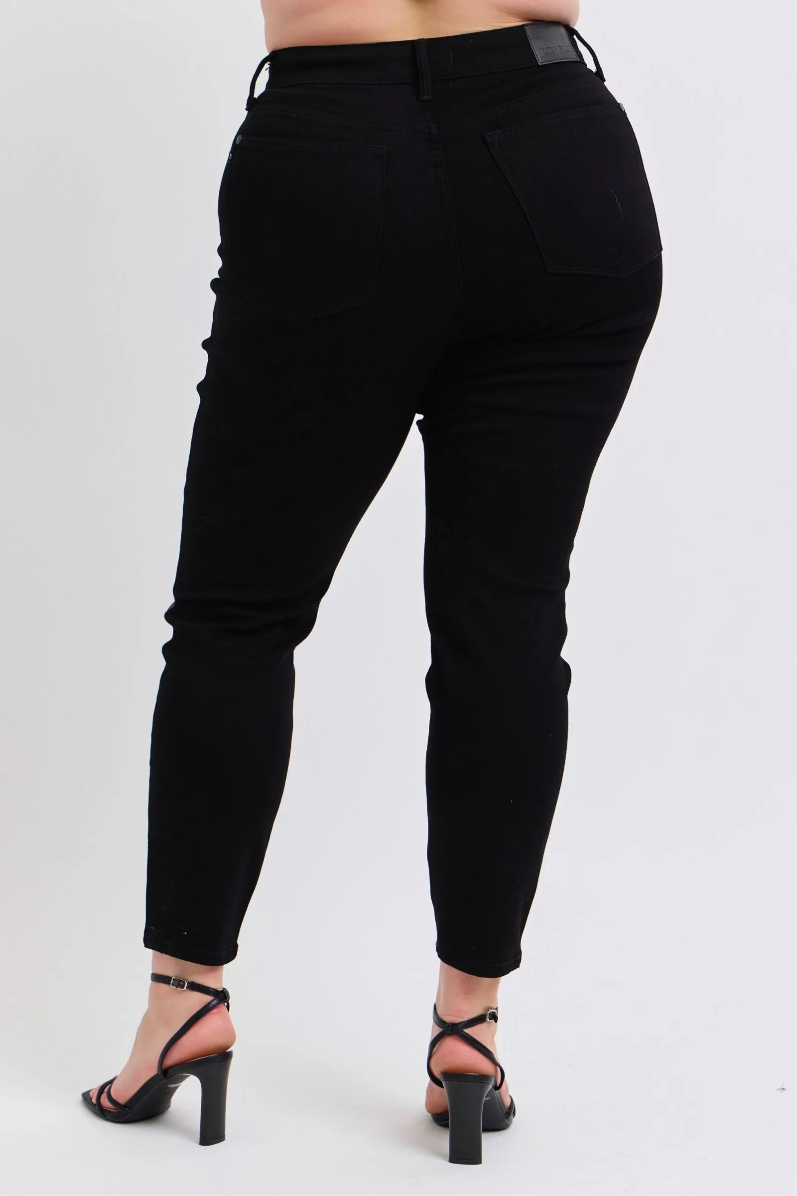 Plus model showing back view of Kat black faux leather skinny pants with high waist, skinny fit, and pocket detail.