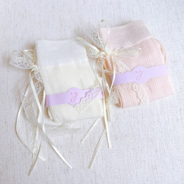 Folded white and pink bow socks highlighting lace trim, satin bows, and soft fabric.